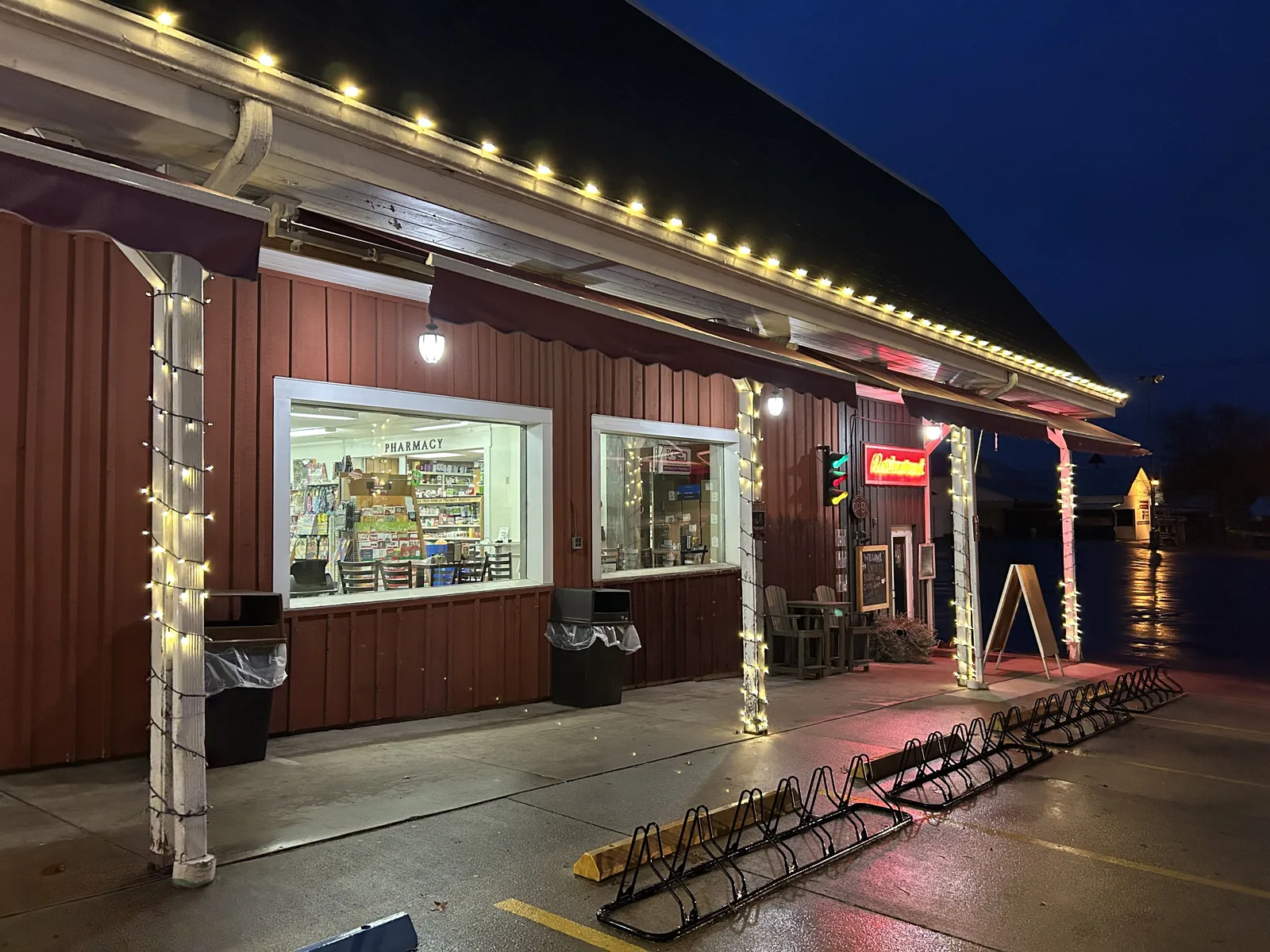 Warm-white Christmas lights tracing a storefront roofline and porch posts
