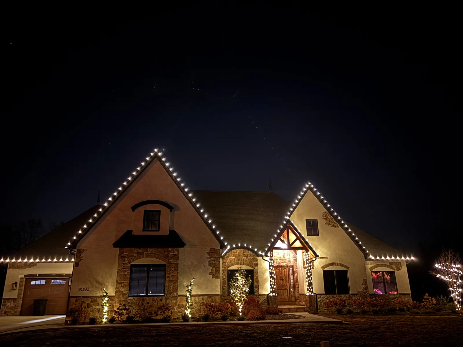 Stone home glowing with warm-white roofline lights at night