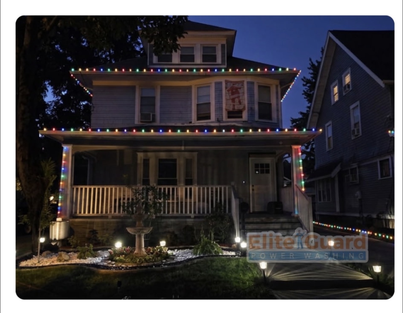 Two-story home outlined in colorful Christmas lights at dusk