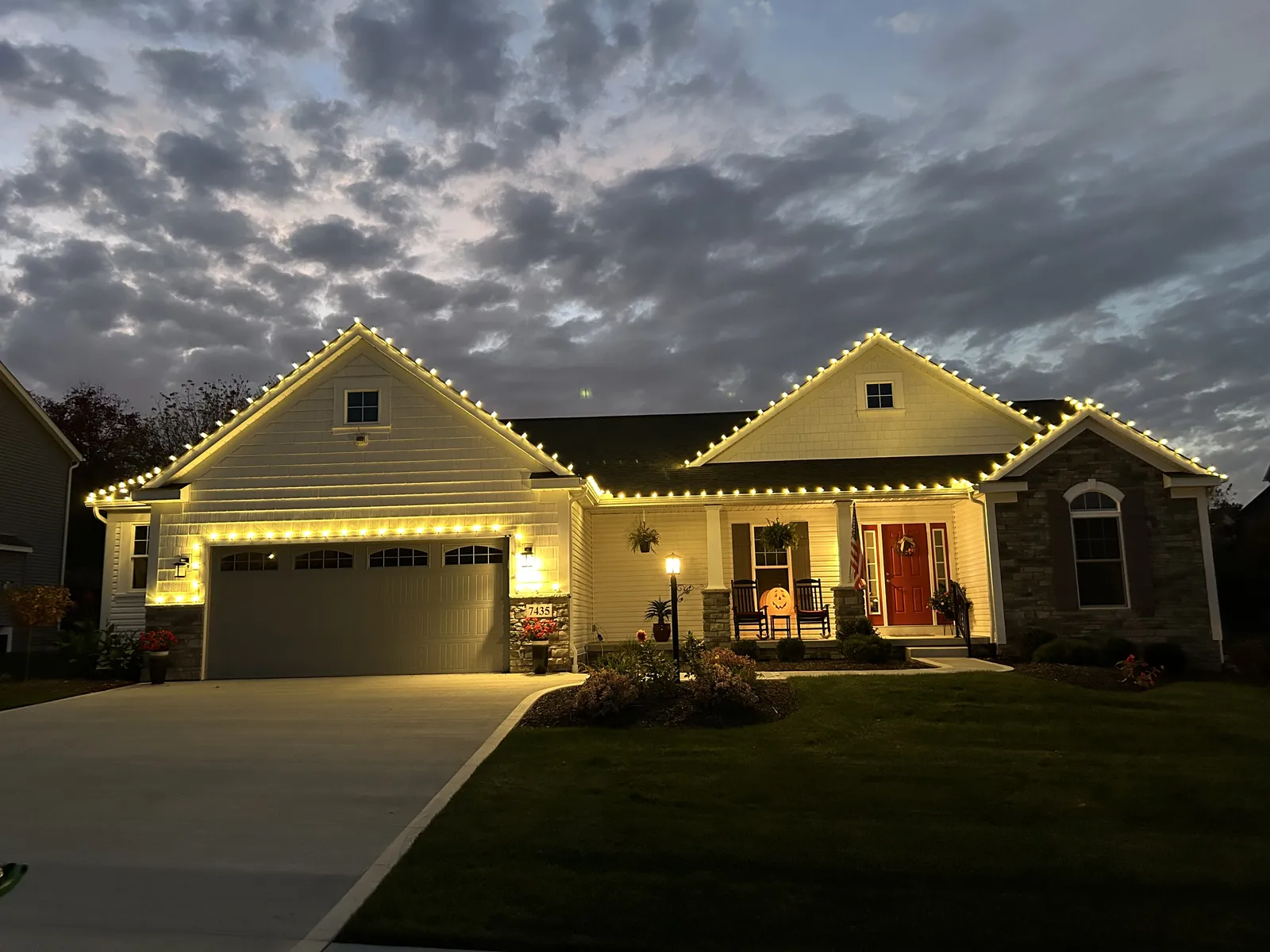 Ranch home with warm-white holiday lighting at dusk