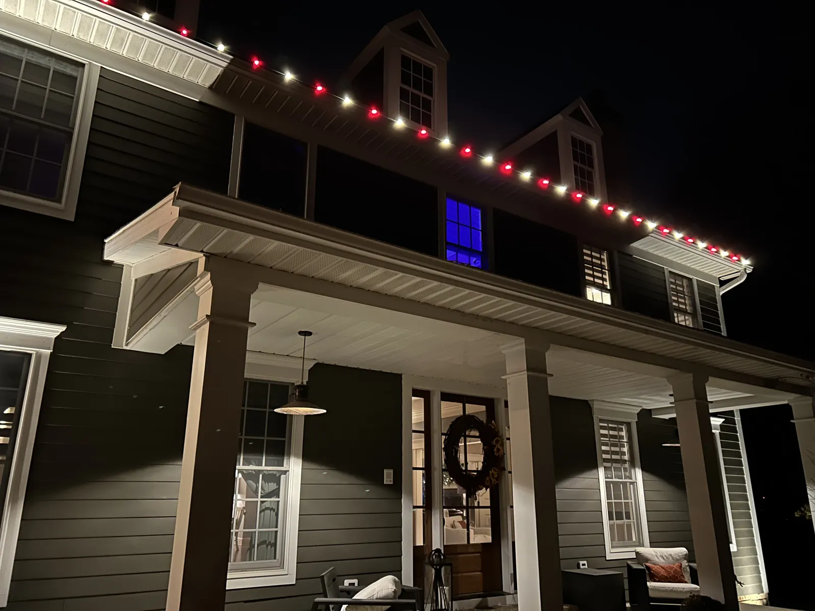 Covered porch with a wreath under red and white roofline lights