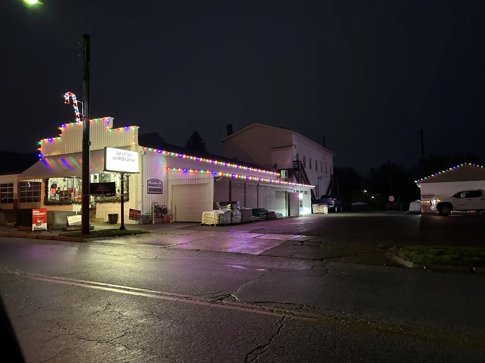 Storefront wrapped in multi-color Christmas lights along the street at night