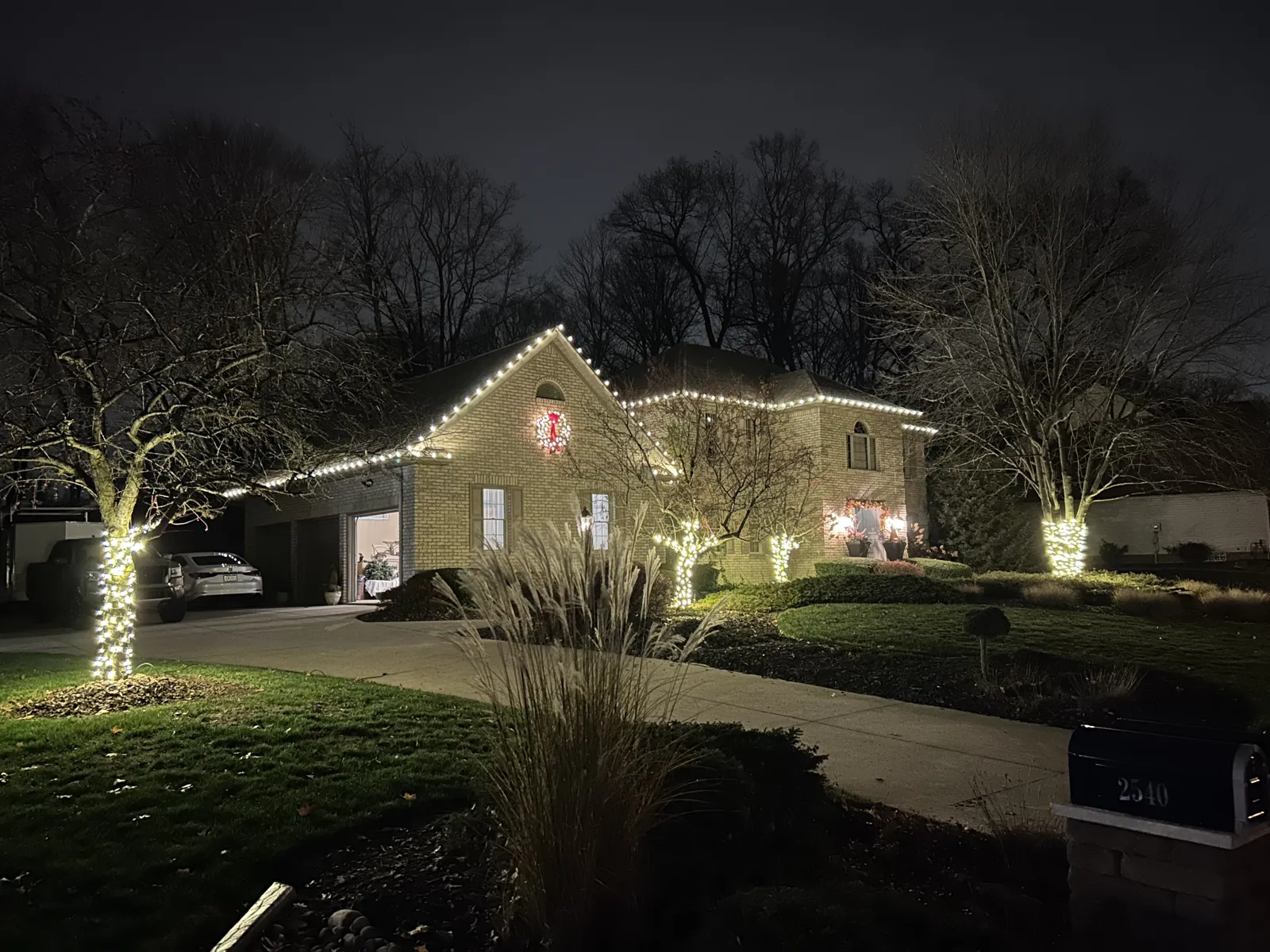 Home with warm-white roofline lights and a glowing tree wrap at night