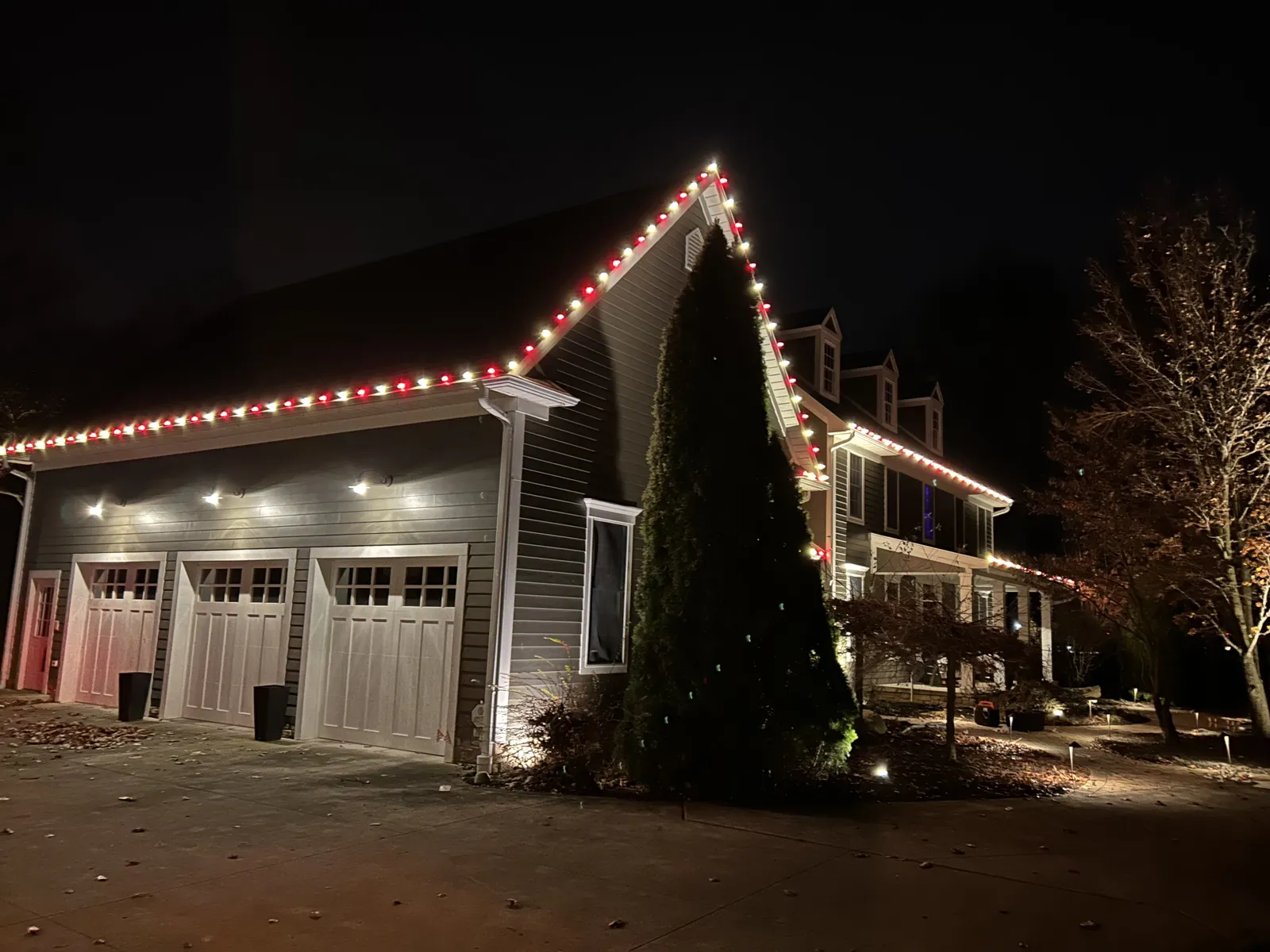 Three-car garage gable outlined in red and white Christmas lights
