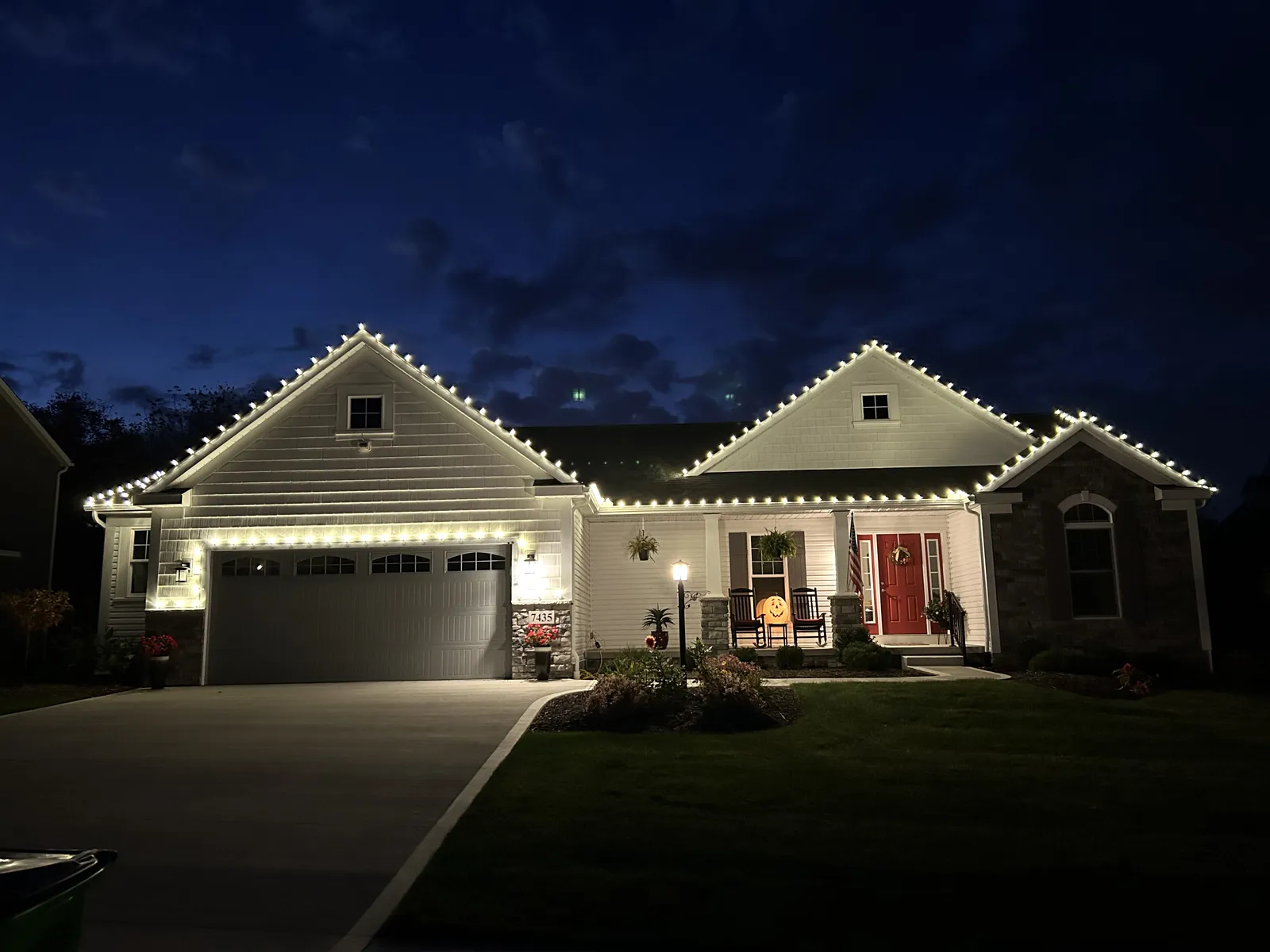 Gray home with warm-white holiday lighting at night