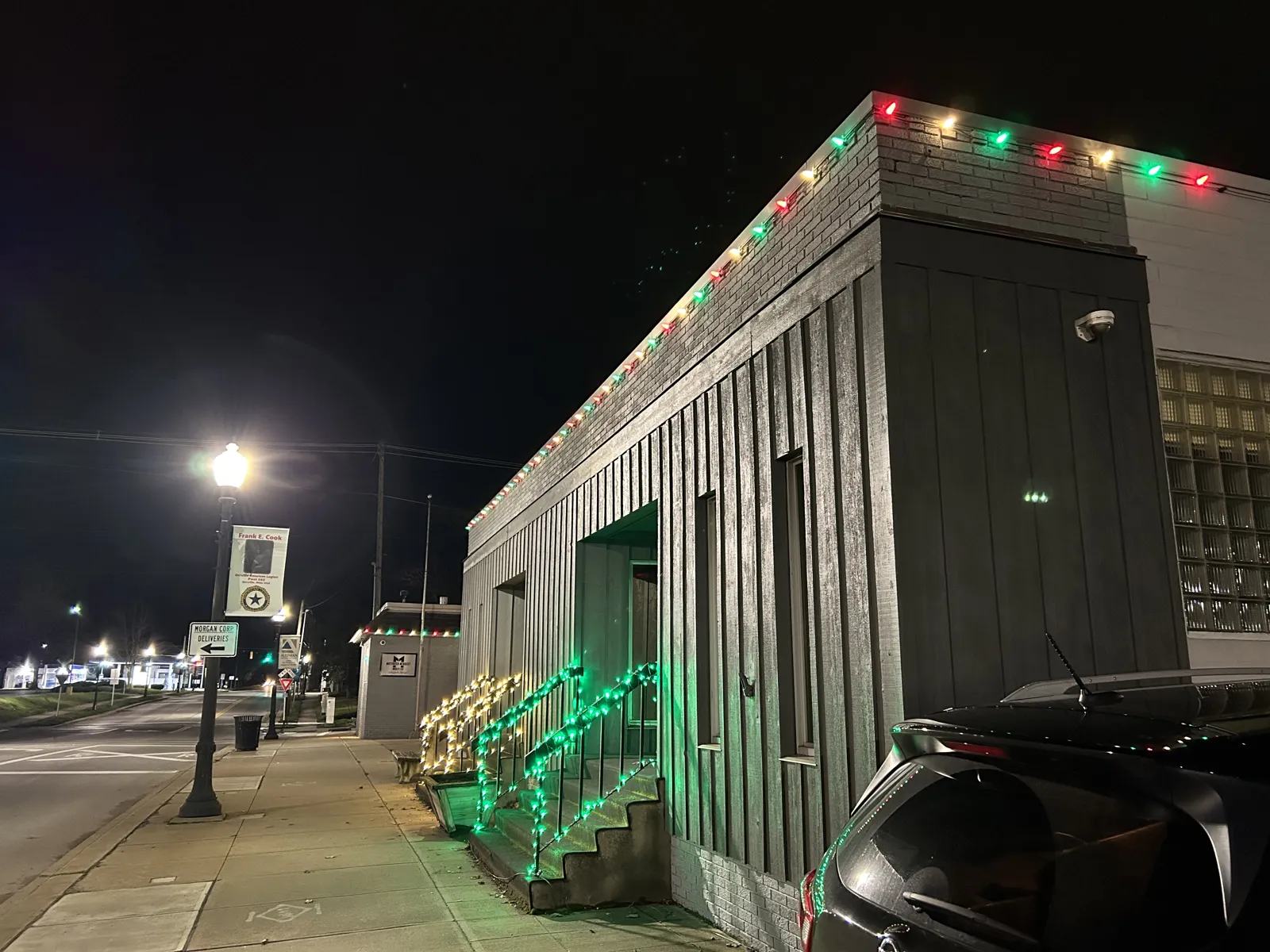 Downtown storefront with red and green roofline lights and lit stair railing