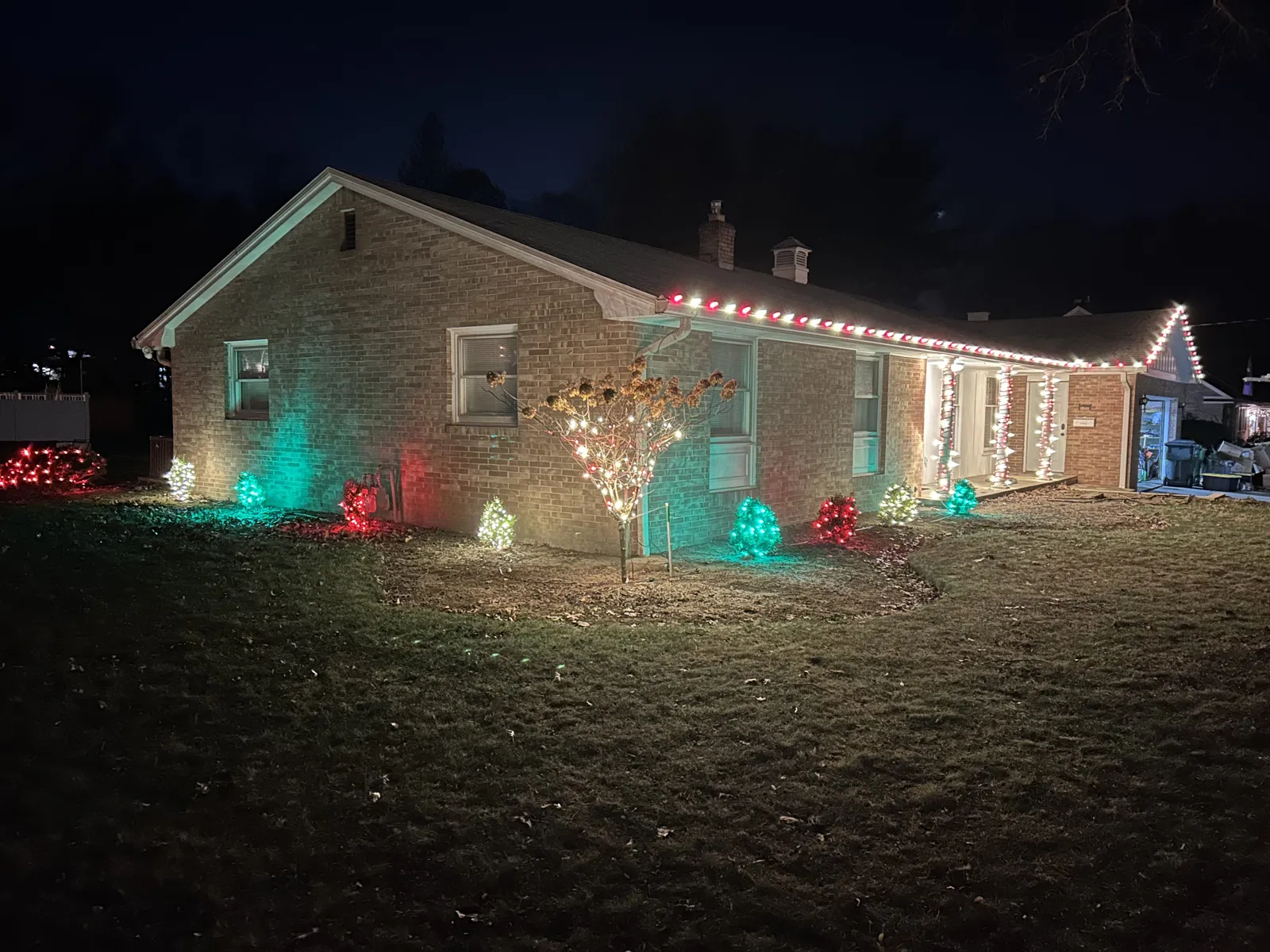 Brick ranch with warm-white roofline and colorful yard lighting