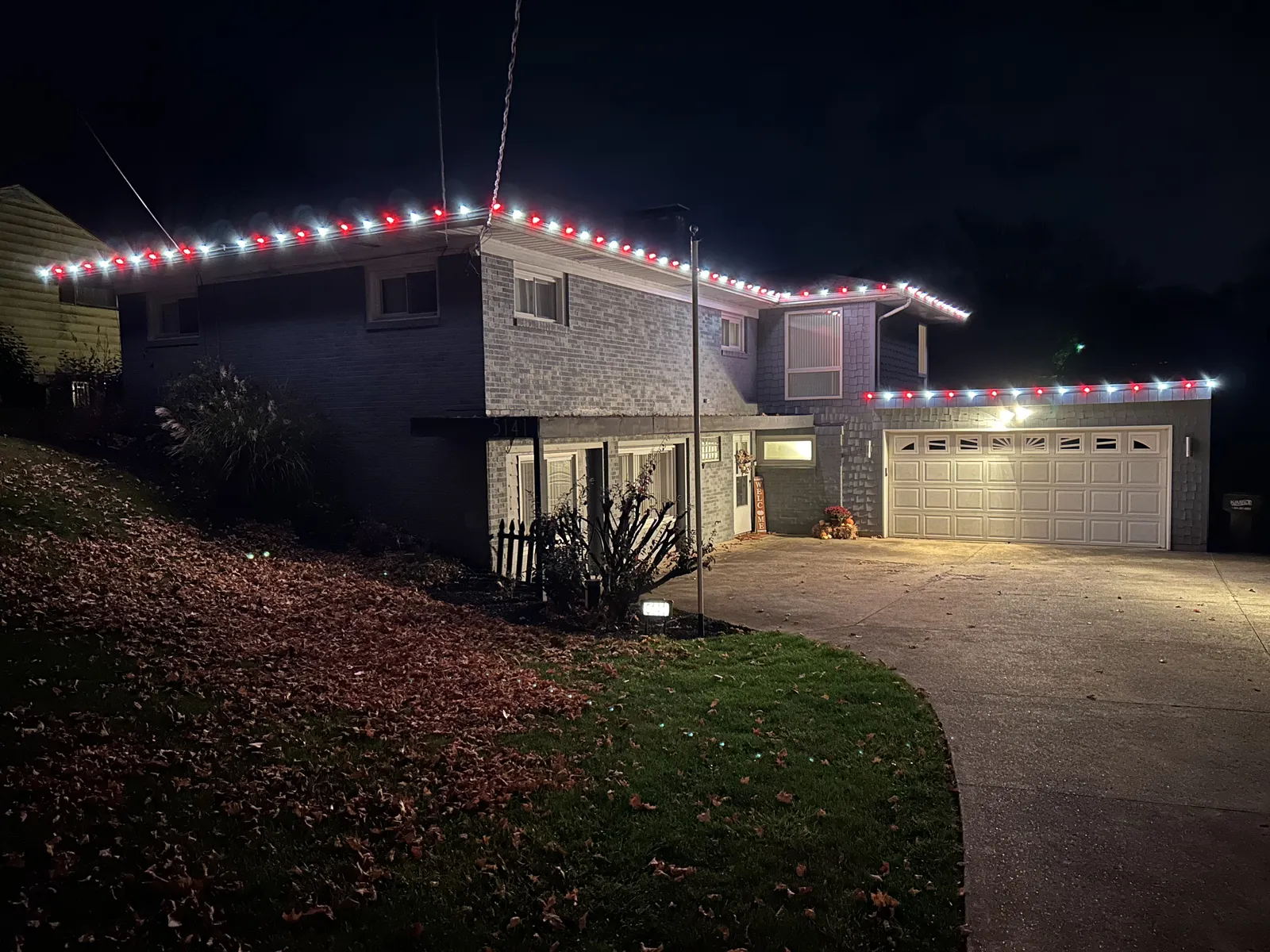 Garage roofline lit with red and white holiday lights at night