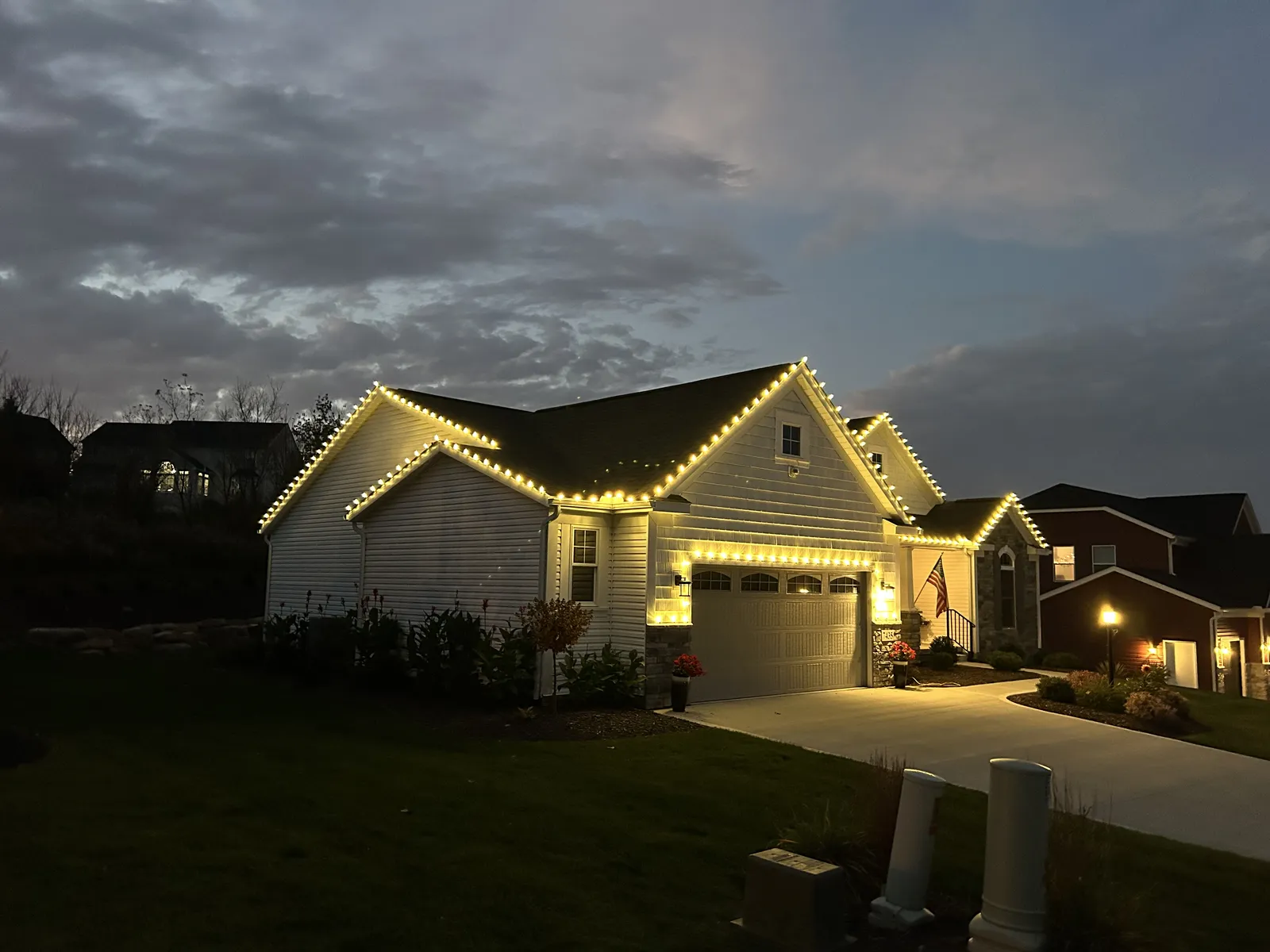 White home wrapped in warm-white roofline lights at night