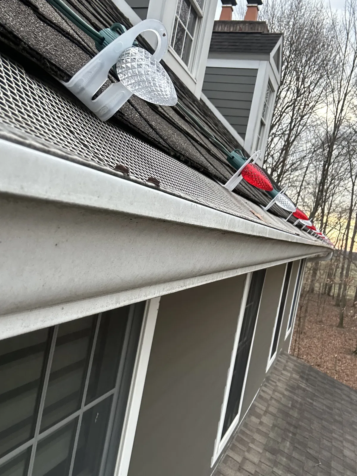 Close-up of a non-penetrating clip holding C9 bulbs on a gutter